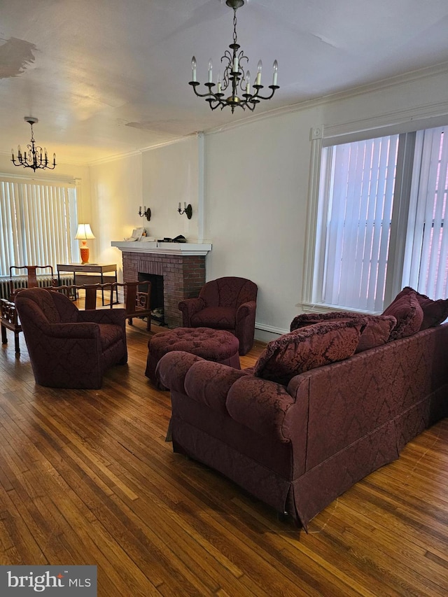 living area featuring a fireplace, crown molding, an inviting chandelier, and wood-type flooring