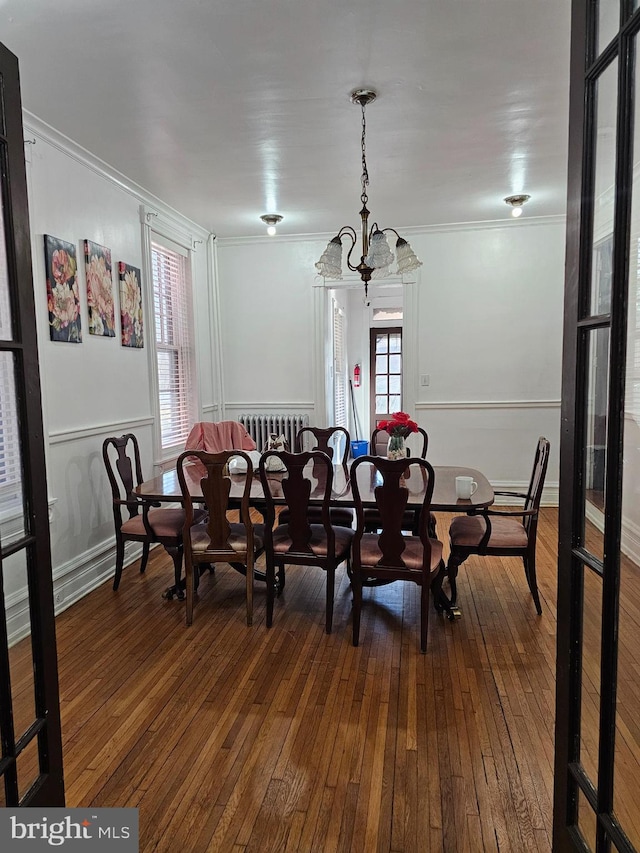 dining area featuring plenty of natural light, wood-type flooring, a notable chandelier, and crown molding