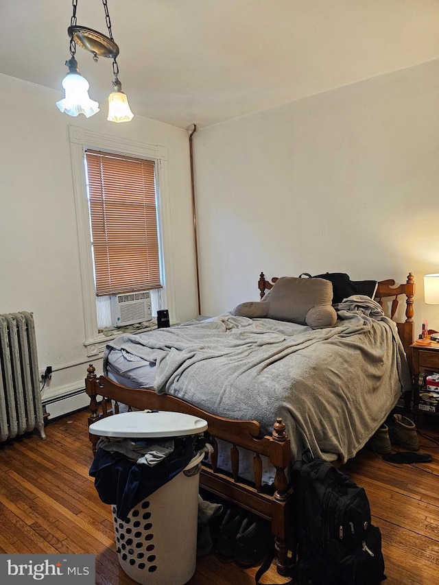 bedroom with baseboard heating, radiator heating unit, cooling unit, and wood-type flooring