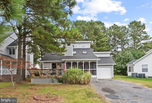 view of front of house with aphalt driveway, cooling unit, a front lawn, and a garage