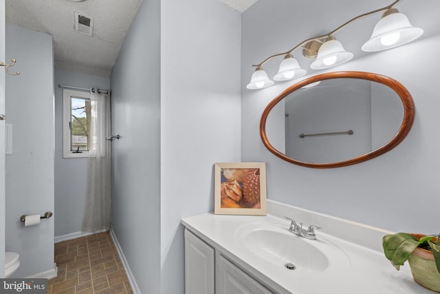 bathroom featuring vanity, baseboards, visible vents, a textured ceiling, and toilet