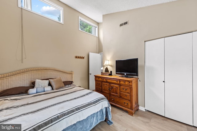 bedroom featuring a closet, visible vents, a textured ceiling, and light wood-type flooring