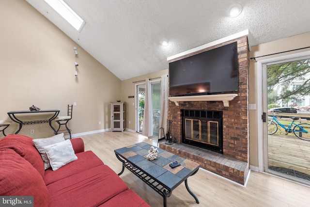 living room featuring vaulted ceiling with skylight, a healthy amount of sunlight, wood finished floors, and a fireplace