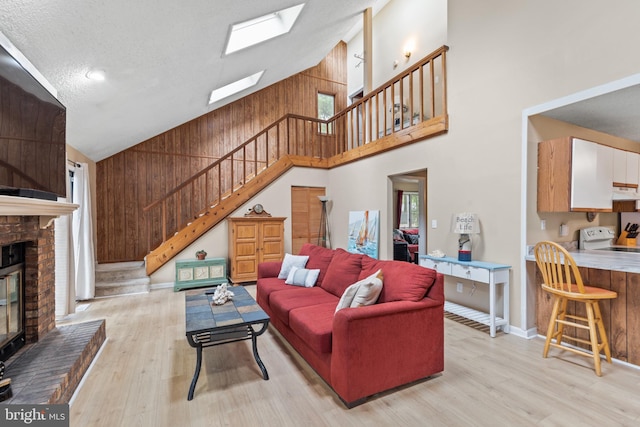 living area with light wood finished floors, stairway, wood walls, and a fireplace