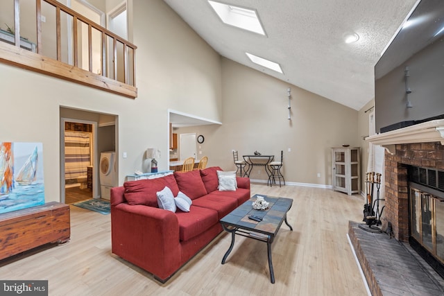 living room with washer / dryer, a fireplace, a skylight, wood finished floors, and a textured ceiling