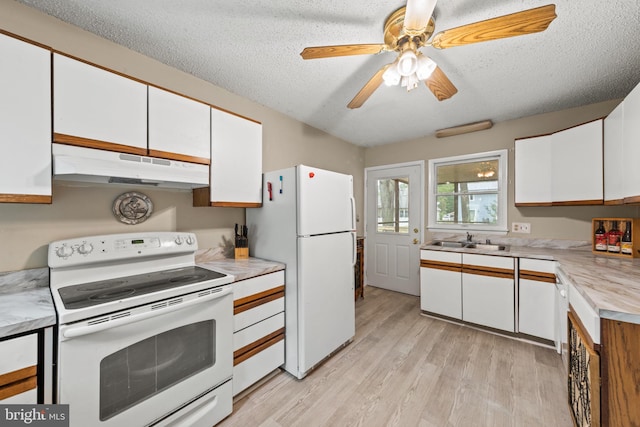 kitchen with white appliances, a sink, light countertops, under cabinet range hood, and white cabinetry