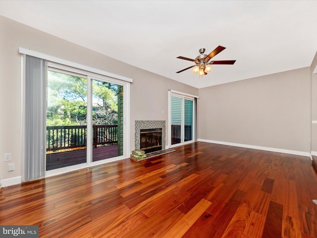 unfurnished living room with baseboards, wood finished floors, visible vents, and a tile fireplace