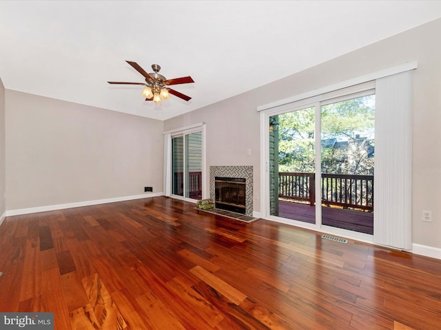 unfurnished living room featuring visible vents, baseboards, a fireplace, wood finished floors, and a ceiling fan