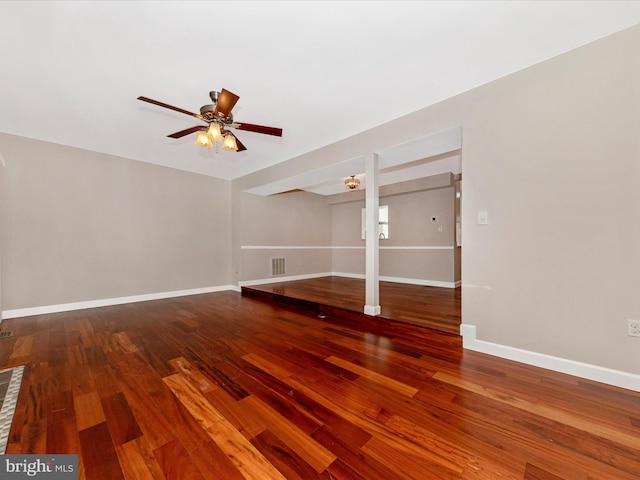 unfurnished living room featuring a ceiling fan, visible vents, wood finished floors, and baseboards