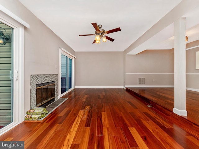 unfurnished living room with visible vents, a fireplace, baseboards, and wood finished floors