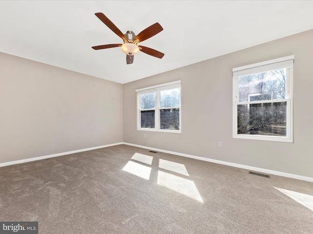 carpeted empty room with baseboards, visible vents, and ceiling fan