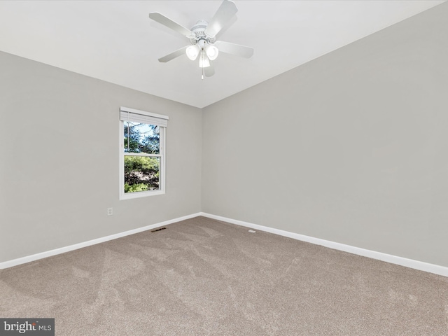 carpeted spare room featuring visible vents, baseboards, and ceiling fan