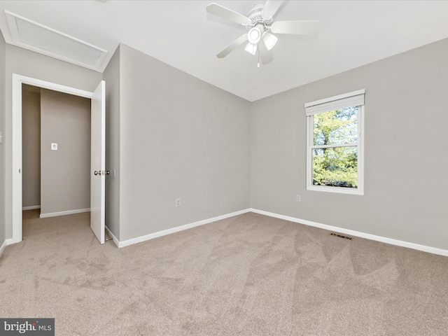 unfurnished bedroom with visible vents, baseboards, carpet, ceiling fan, and attic access