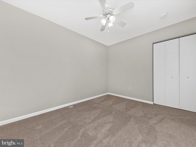 unfurnished bedroom with a closet, carpet flooring, a ceiling fan, and baseboards