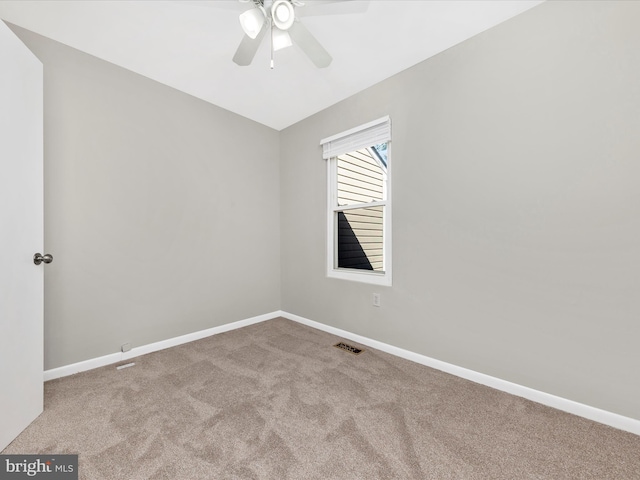 carpeted spare room featuring visible vents, baseboards, and ceiling fan