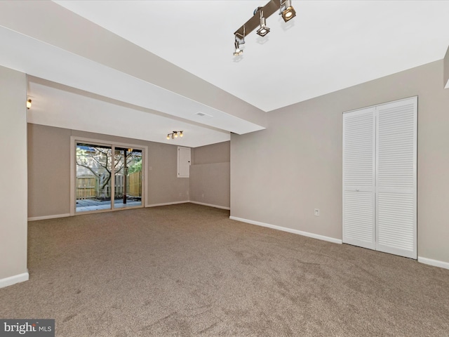 unfurnished living room featuring track lighting, baseboards, and carpet