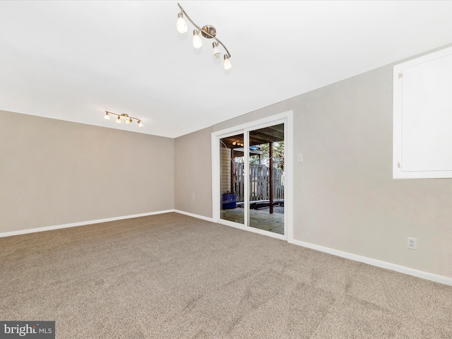 carpeted empty room featuring baseboards and rail lighting