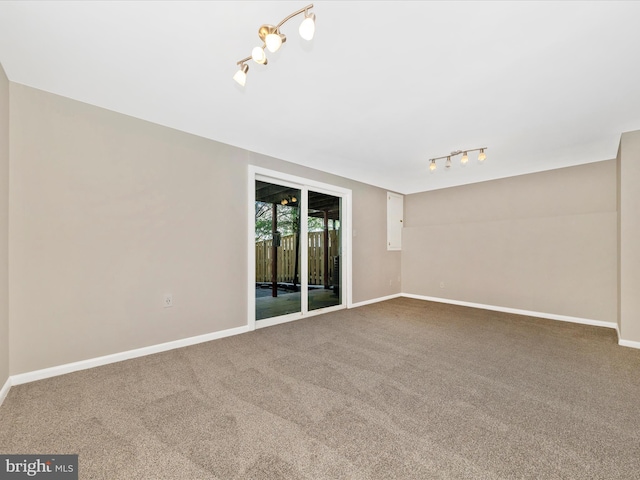 carpeted spare room featuring rail lighting and baseboards