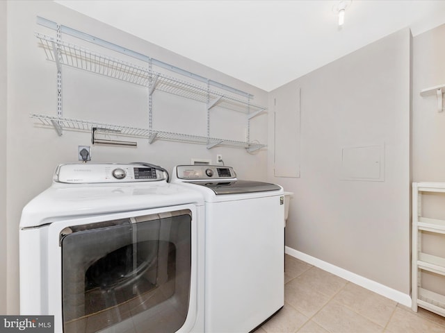 laundry area with light tile patterned floors, baseboards, laundry area, and washing machine and clothes dryer