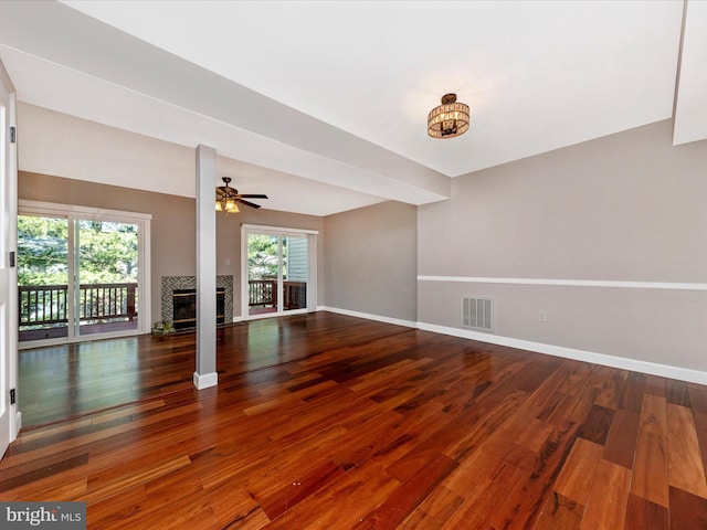 unfurnished living room with visible vents, a ceiling fan, hardwood / wood-style flooring, baseboards, and a tile fireplace