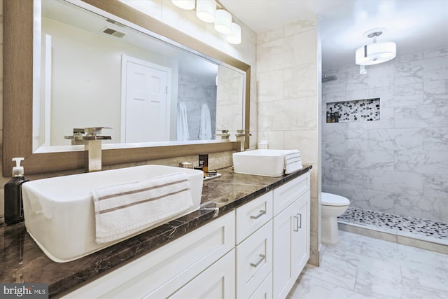 bathroom with a sink, marble finish floor, and a tile shower