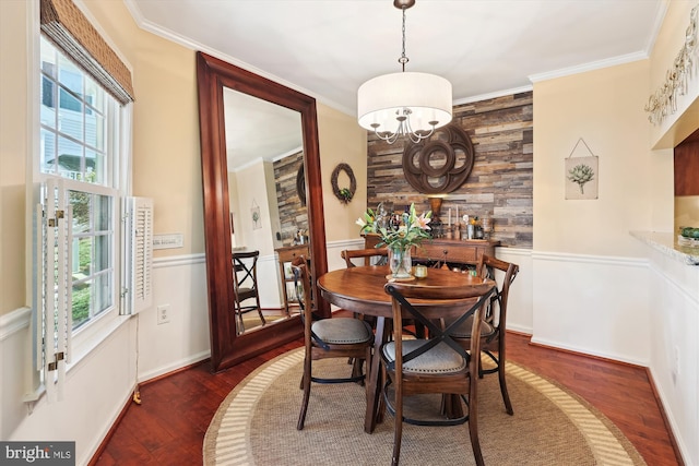 dining room with a notable chandelier, wood finished floors, wood walls, and ornamental molding