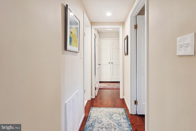 hall featuring dark wood-style floors, visible vents, and baseboards