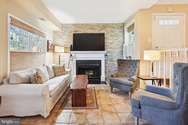 living room featuring light tile patterned floors, a fireplace with flush hearth, and visible vents