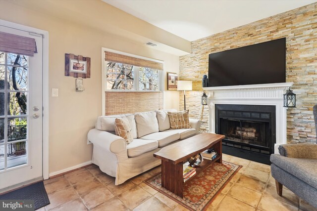 living area with a fireplace with flush hearth, baseboards, and visible vents