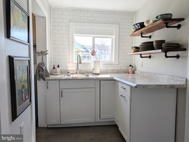 kitchen featuring open shelves, dark wood-type flooring, backsplash, and a sink