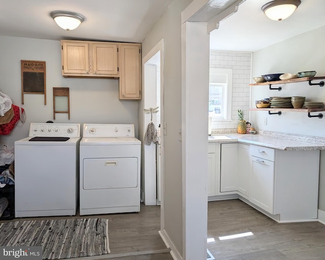 washroom featuring wood finished floors, cabinet space, and washing machine and dryer