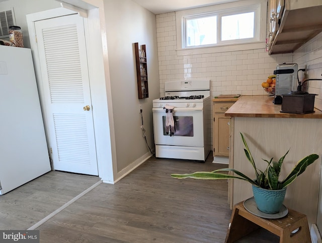 kitchen featuring white appliances, dark wood-style floors, baseboards, wooden counters, and tasteful backsplash