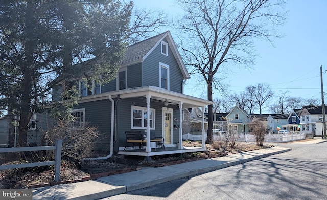 view of front of home featuring fence, covered porch, a residential view, and roof with shingles