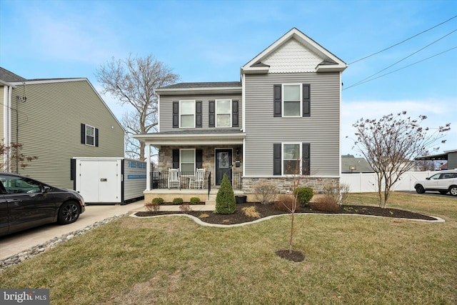 view of front facade featuring a front yard, fence, covered porch, and stone siding