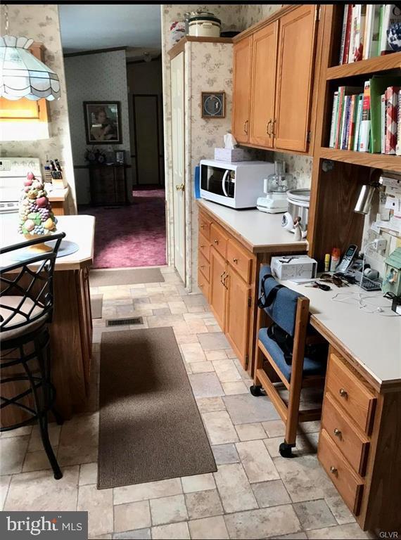 kitchen with white microwave, wallpapered walls, and light countertops