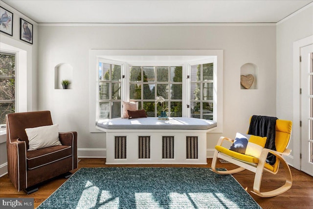 sitting room with a healthy amount of sunlight, ornamental molding, and wood finished floors