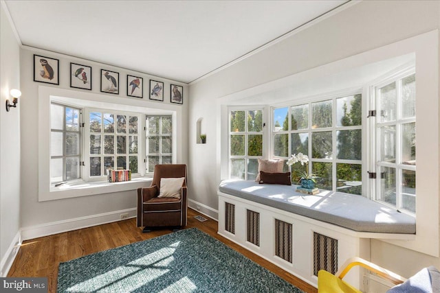 living area featuring visible vents, crown molding, baseboards, and wood finished floors