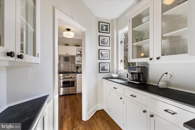 kitchen with dark countertops, glass insert cabinets, high end stainless steel range, and dark wood-style flooring