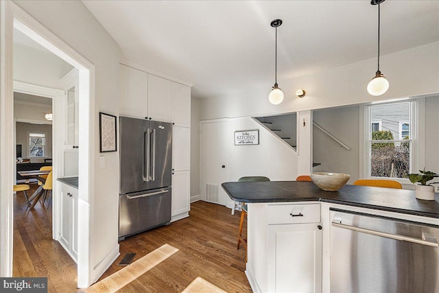 kitchen featuring dark countertops, white cabinets, dark wood finished floors, and stainless steel appliances