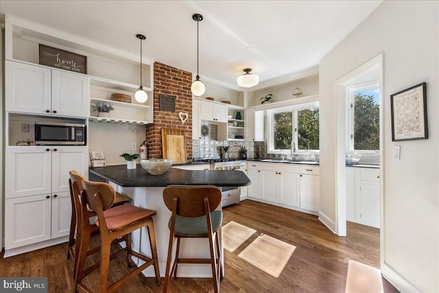 kitchen with dark countertops, stainless steel microwave, stove, and open shelves