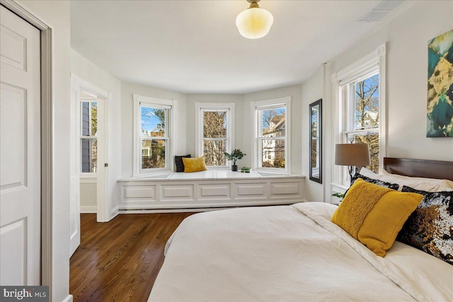 bedroom with dark wood finished floors, multiple windows, and visible vents