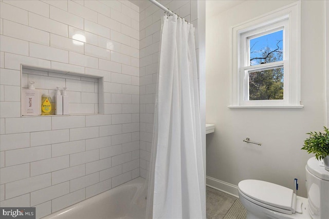 bathroom with baseboards, toilet, and shower / bath combo