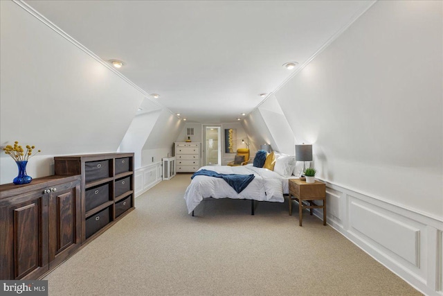 bedroom featuring a decorative wall, light colored carpet, crown molding, and lofted ceiling