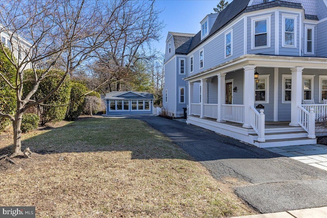 view of property exterior with a yard, covered porch, and an outdoor structure