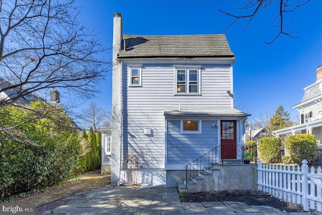 view of front of home featuring a chimney and fence