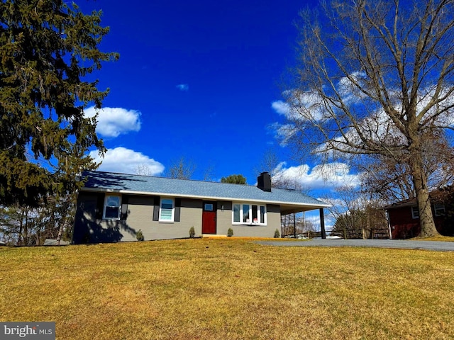 single story home featuring a carport, a front yard, driveway, and a chimney