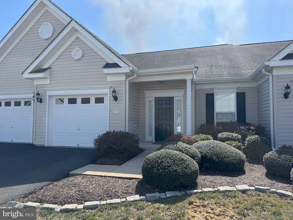 ranch-style home with an attached garage, driveway, and a shingled roof