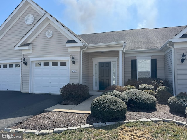 ranch-style home with an attached garage, driveway, and a shingled roof