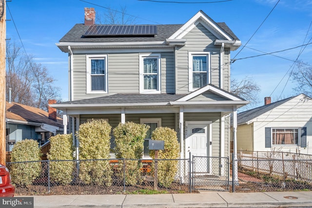 view of front of property featuring solar panels, a shingled roof, a fenced front yard, a porch, and a gate