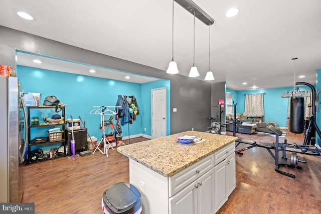 kitchen featuring wood finished floors, a center island, open floor plan, freestanding refrigerator, and white cabinets